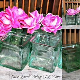 Pink roses in clear glass cube vases on a table, with a vintage collage-style background