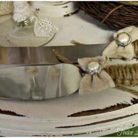 Decorative place setting with silverware, lace bows, and a white plate on a rustic table