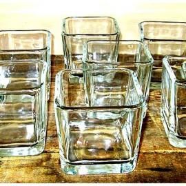 Clear square glass tumblers arranged on a wooden surface