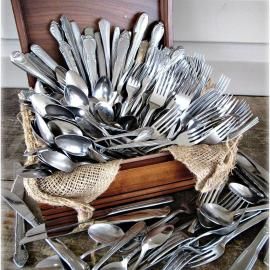 Stacked silverware in wooden crates, with spoons, forks, and knives wrapped in burlap.