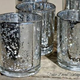 Three textured silver candle holders on a wooden surface