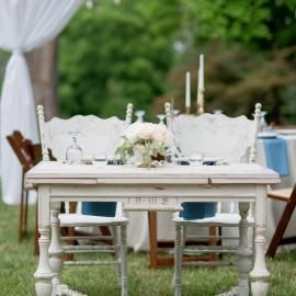 White outdoor dining table set for an elegant garden event with flowers and candles