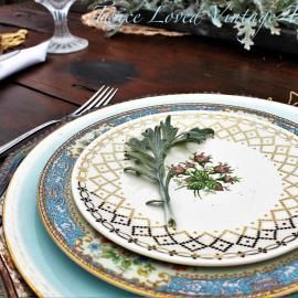 Elegant table setting with patterned plates, green leaf napkin ring, and silverware on a wooden table