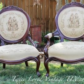 Pair of lavender vintage accent chairs with cream upholstery and floral medallions in a wood-paneled room