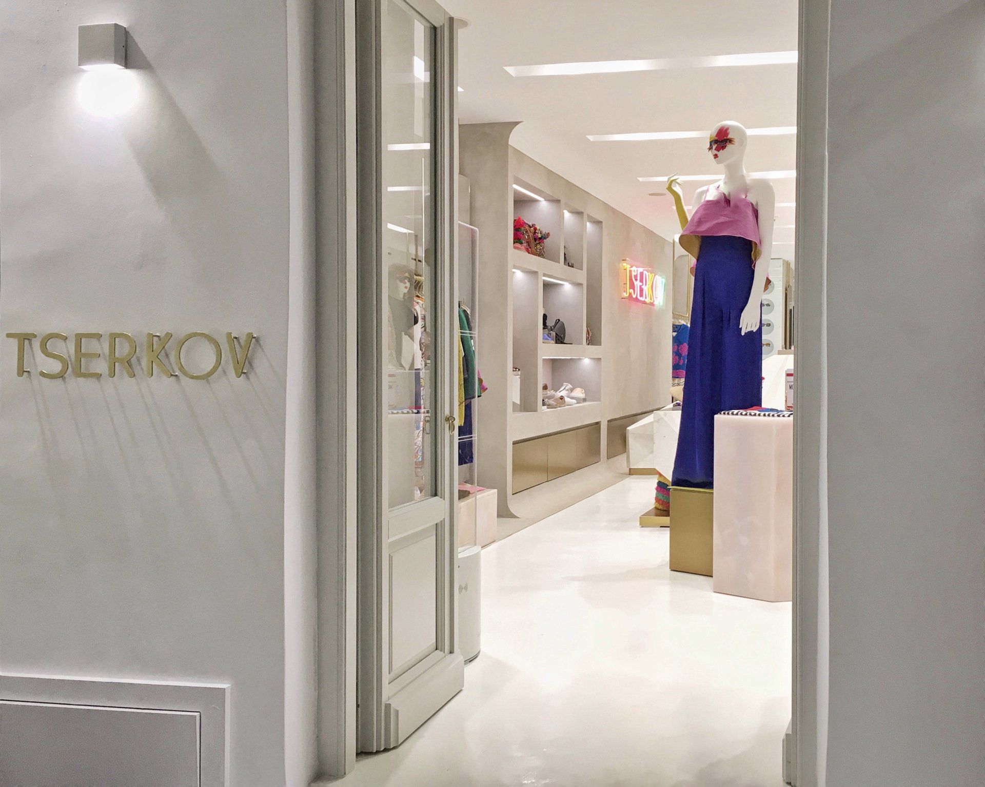 A clothing boutique with a mannequin wearing blue pants and pink top. Gold lettering above the door.