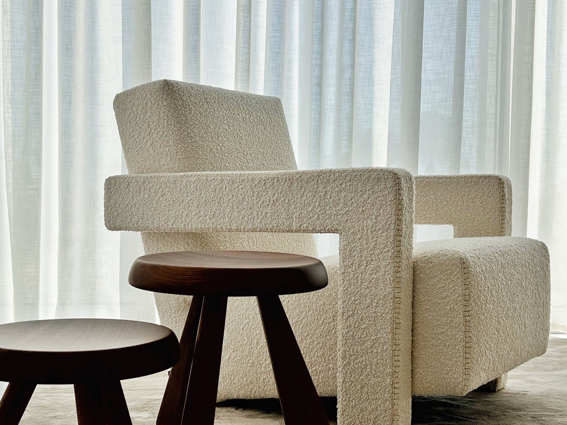 Cream bouclé designer armchair with wooden side table from Cassina and sheer curtains