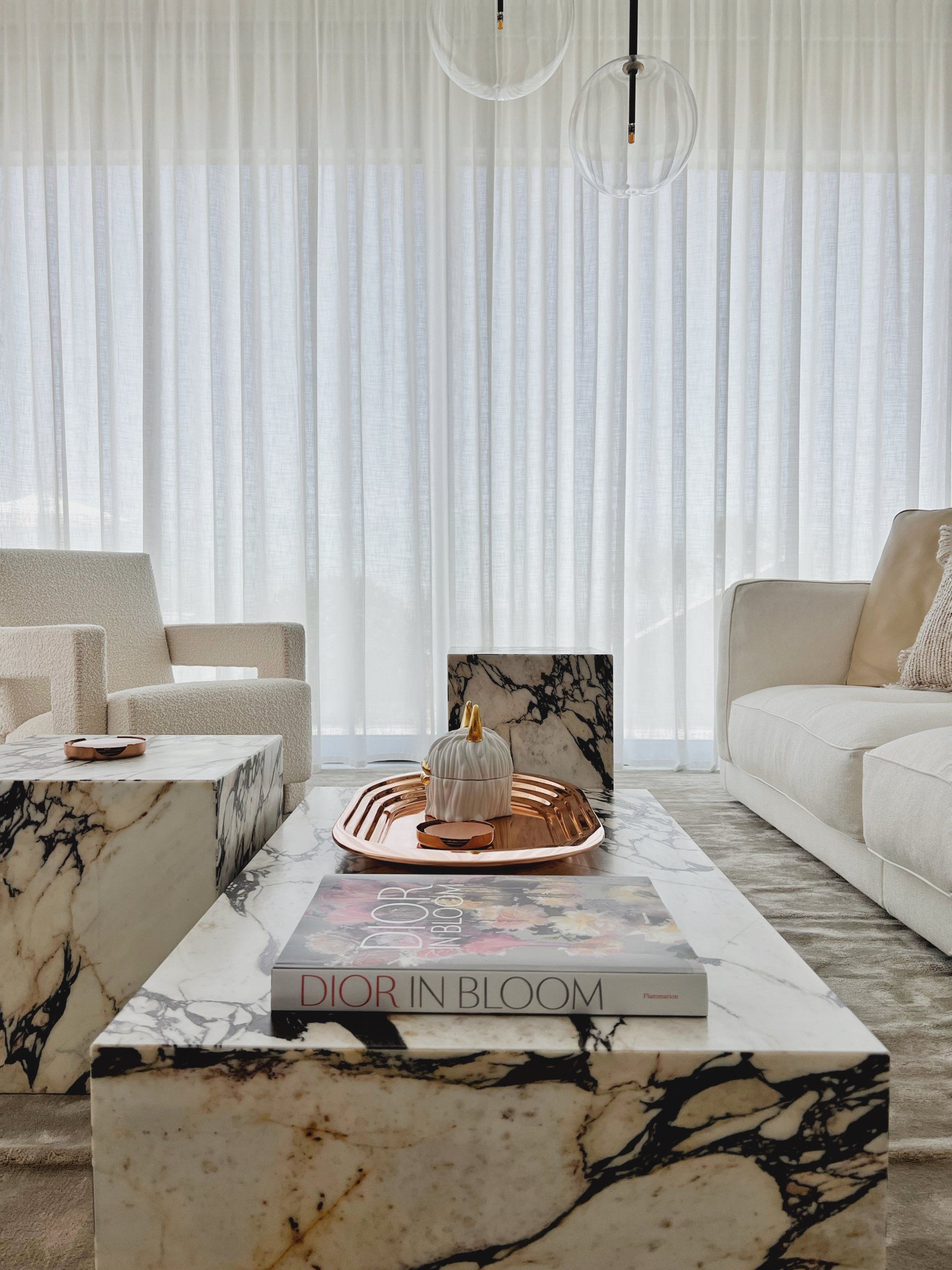 Sheer white curtains and designer lighting in a bright luxury living room