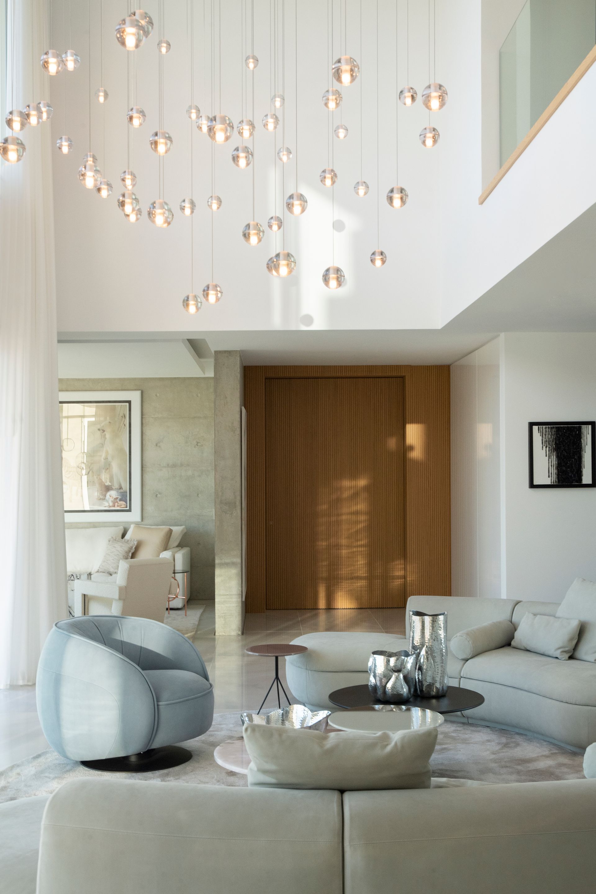 Beige living room with designer armchair, marble tables and pendant lights