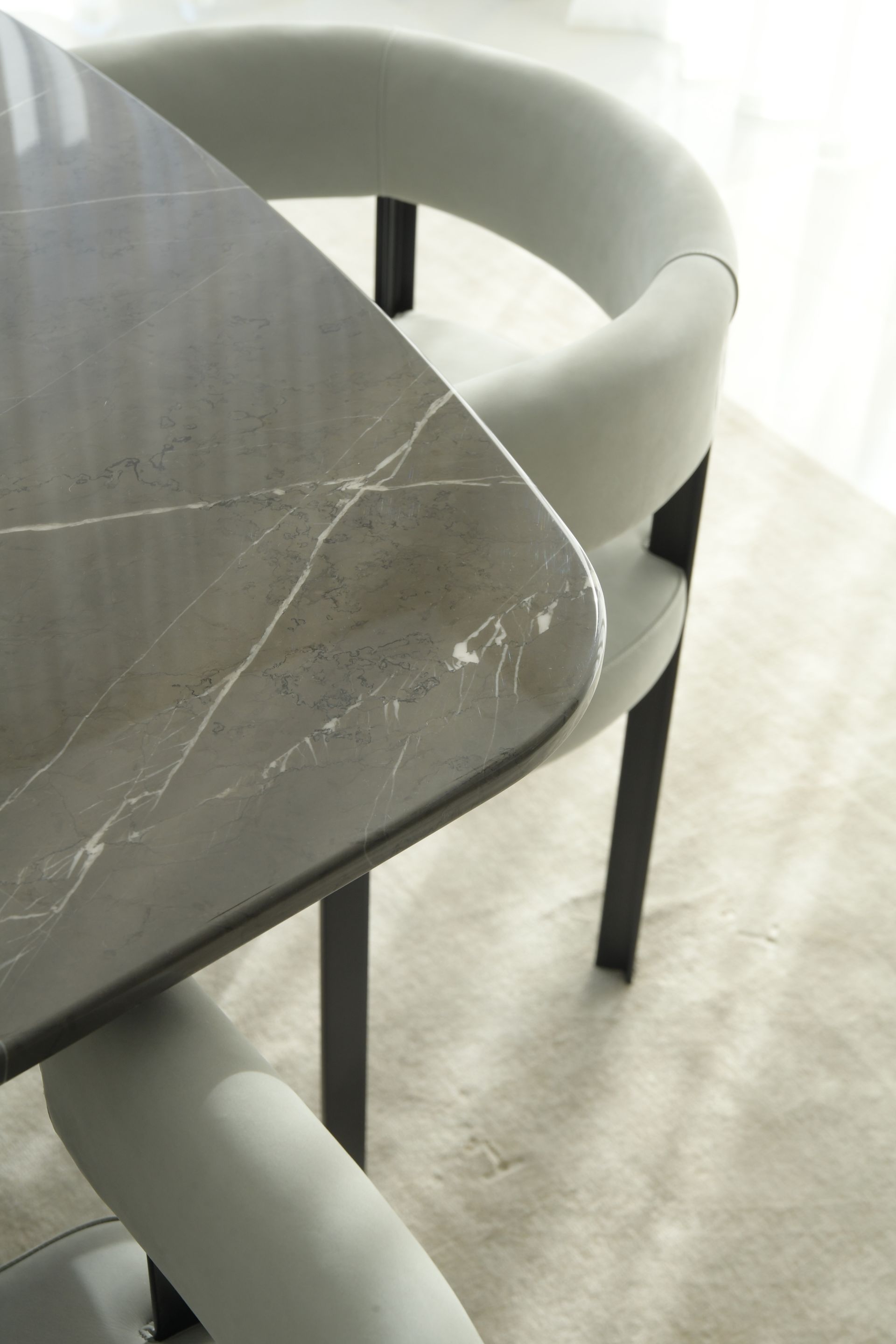 Gray marble dining table with curved upholstered chair in a luxury interior