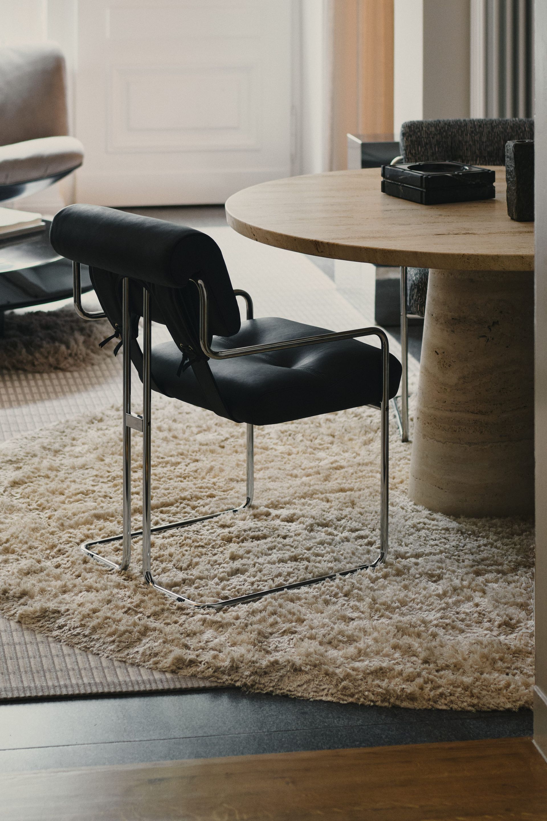 Black chair and round stone table in the contemporary interior of the DÉMARTISTUDIO Berlin showroom