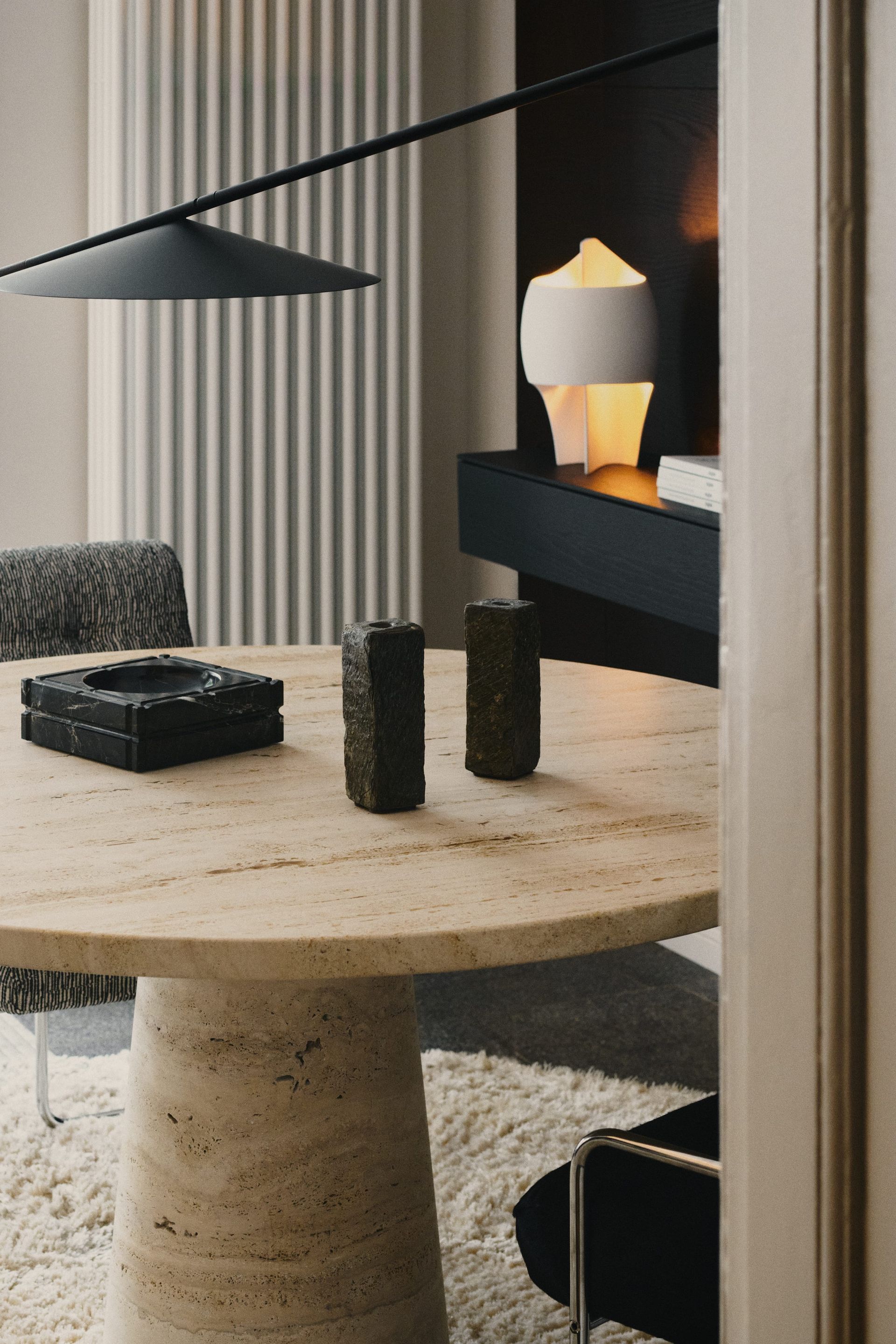 Round stone table with black pendant lamp and side table at the DÉMARTISTUDIO showroom in Berlin