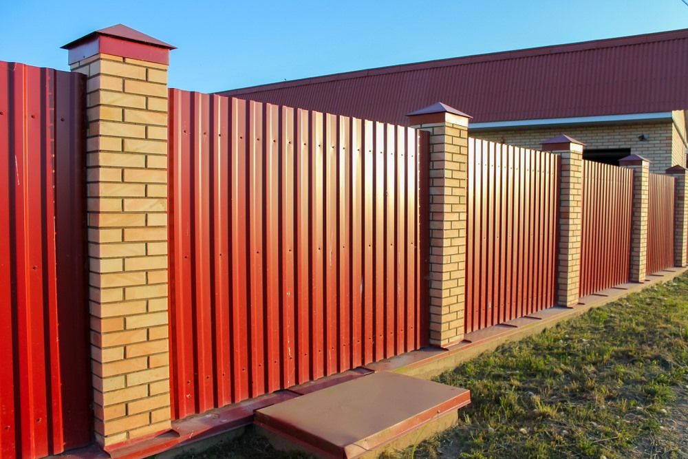 A Red Fence With Brick Posts In Front Of A House — Ballina Best Fencing In Northern Rivers, NSW