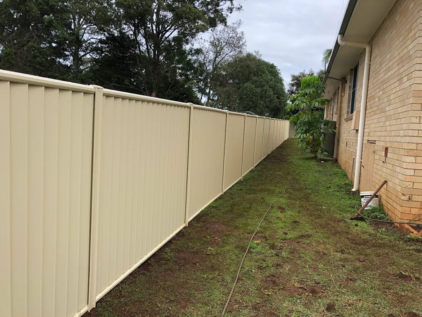 a colour bound fence that is cream coloured next to a house— Ballina Best Fencing In Ballina, NSW