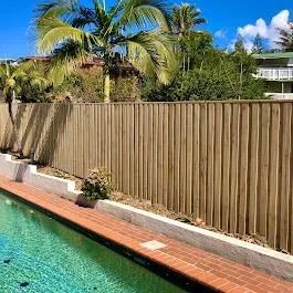 A Wooden Fence Is Surrounded By Grass And Rocks — Ballina Best Fencing In Ballina, NSW
