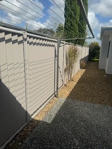 A Green Fence With A Gate In Front Of A House — Ballina Best Fencing In Ballina, NSW