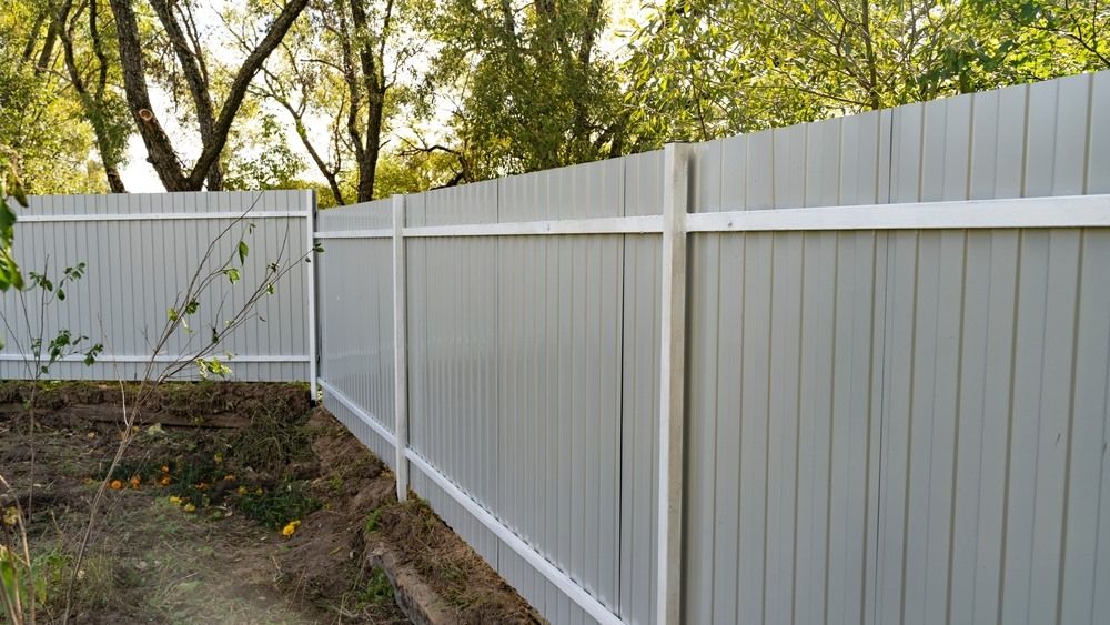 A Gray Fence With A White Trim Is Surrounded By Trees — Ballina Best Fencing In Alstonville, NSW