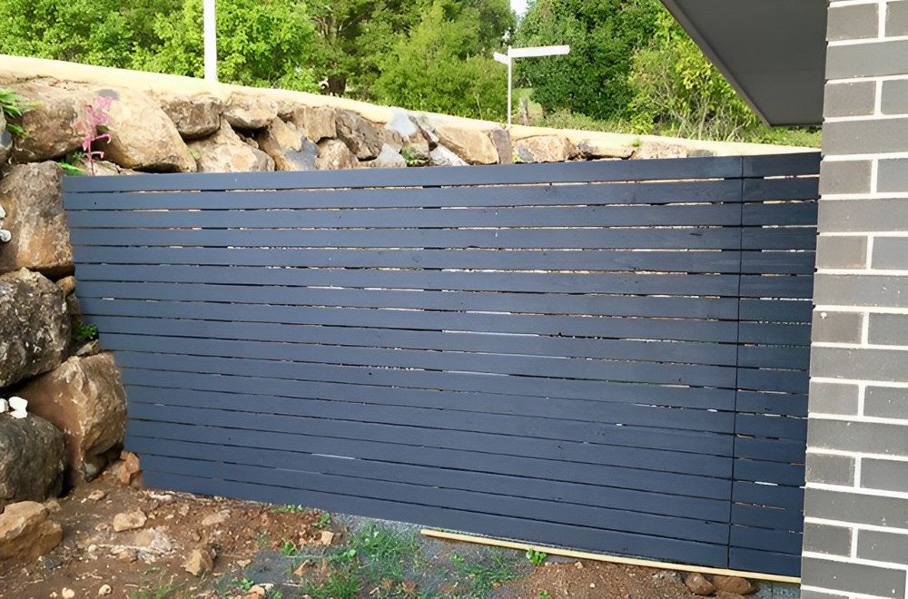 A Wooden Fence Surrounds A Garden — Ballina Best Fencing In Ballina, NSW