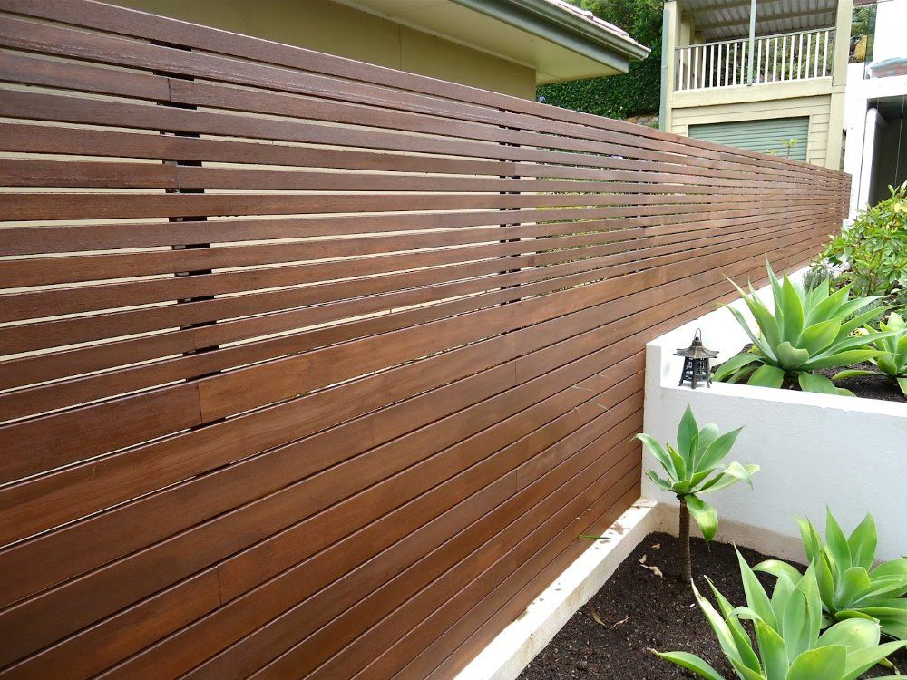 A Wooden Fence Surrounds A Garden In Front Of A House — Ballina Best Fencing In Ballina, NSW