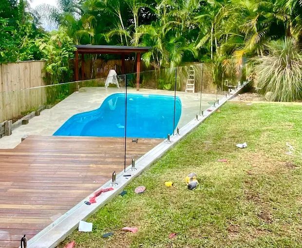 A Glass Railing With A Stainless Steel Railing On A Sidewalk — Ballina Best Fencing In Ballina, NSW