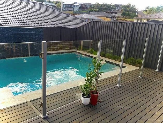 A Concrete Wall With A Glass Railing On It — Ballina Best Fencing In Ballina, NSW