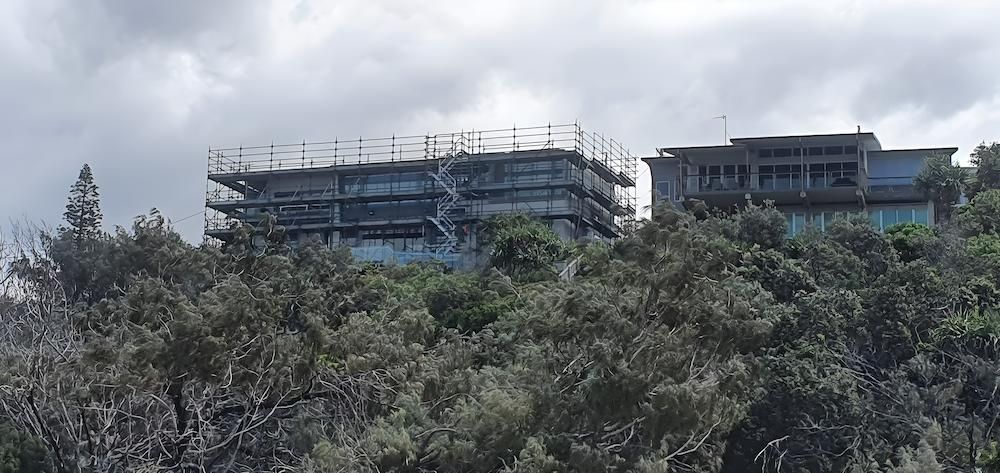 A Large Building is Being Built on Top of a Hill Surrounded by Trees — All Coast Scaffolding In Yandina, QLD