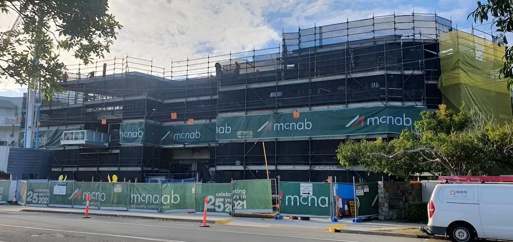 A White Van is Parked in Front of a Large Building Under Construction — All Coast Scaffolding In Yandina, QLD