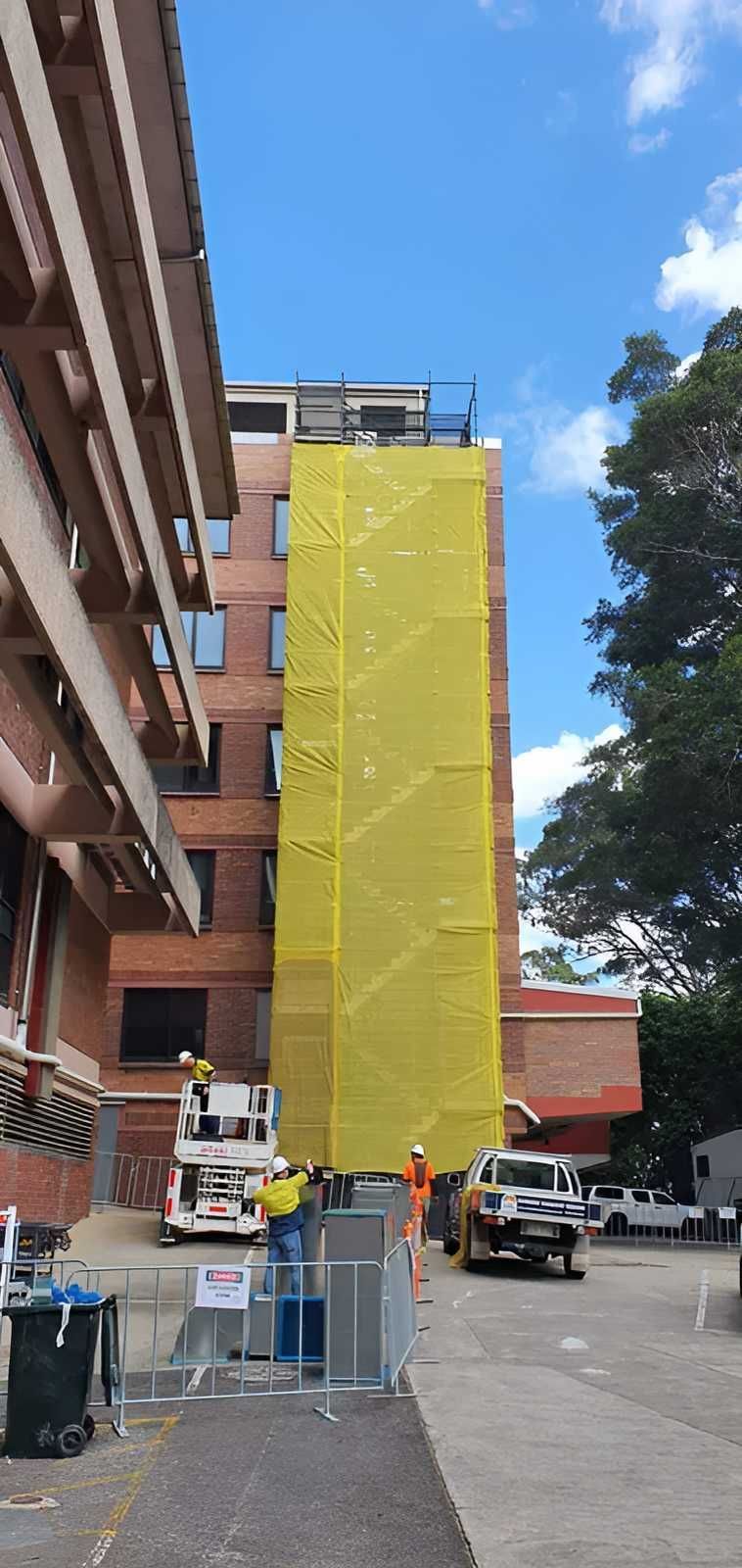 A Large Building is Being Covered in Yellow Tarps — All Coast Scaffolding In Yandina, QLD