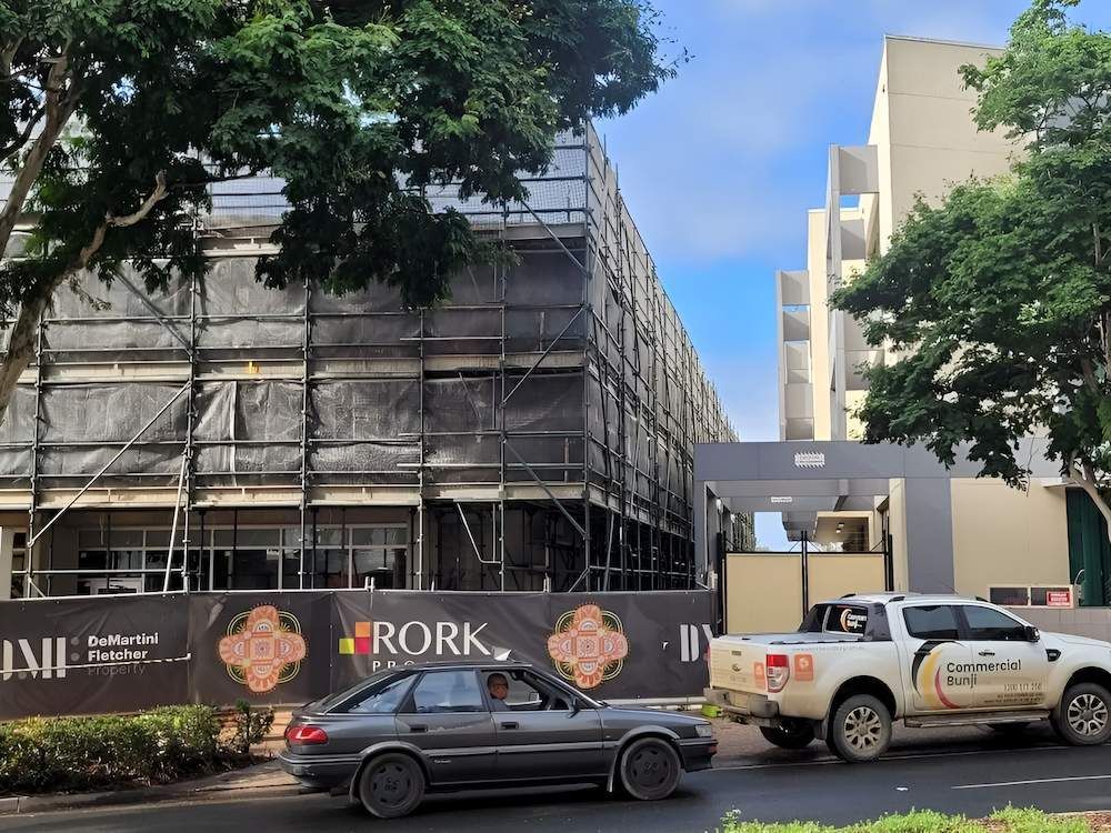 A Car is Driving Down a Street in Front of a Building Under Construction — All Coast Scaffolding In Yandina, QLD