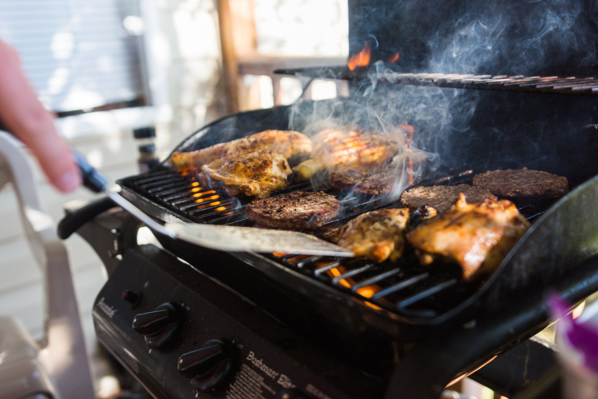 Someone safely grilling delicious food on a propane grill top.