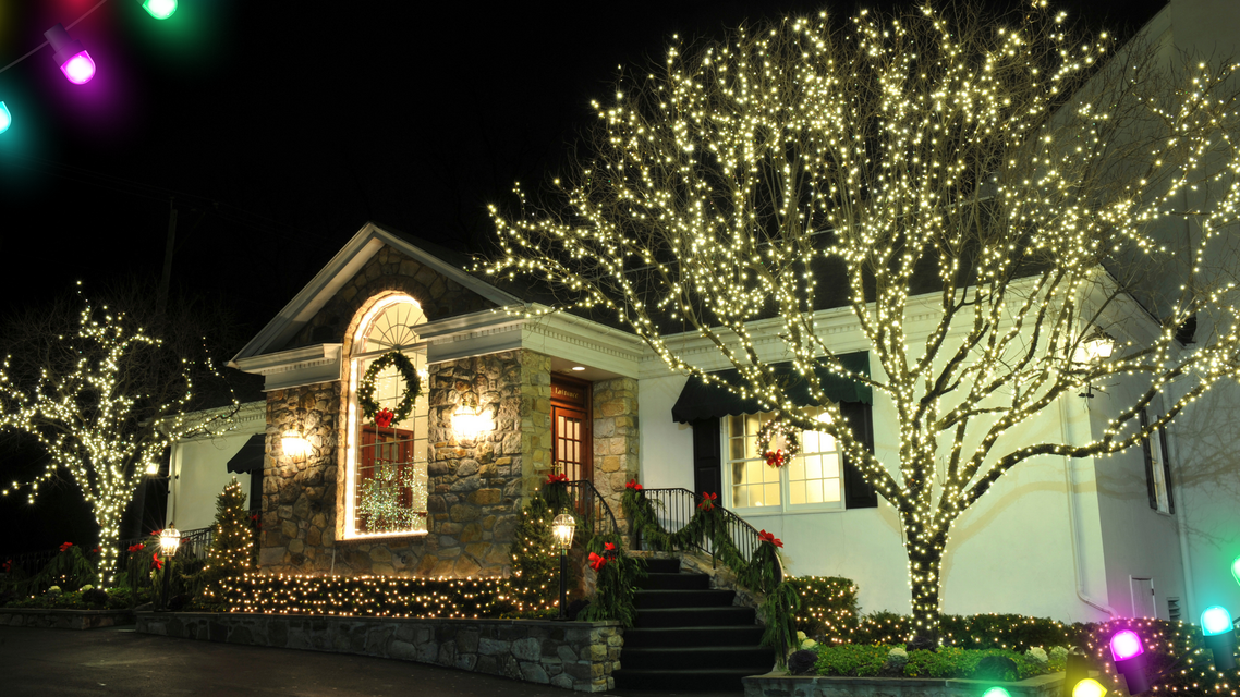 A house at night, decorated with Christmas lights and wreaths.