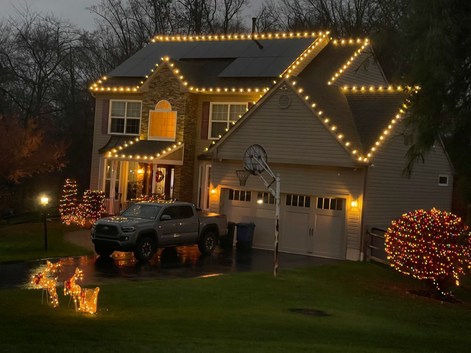 House decorated with Christmas lights and wreaths, illuminated at night.