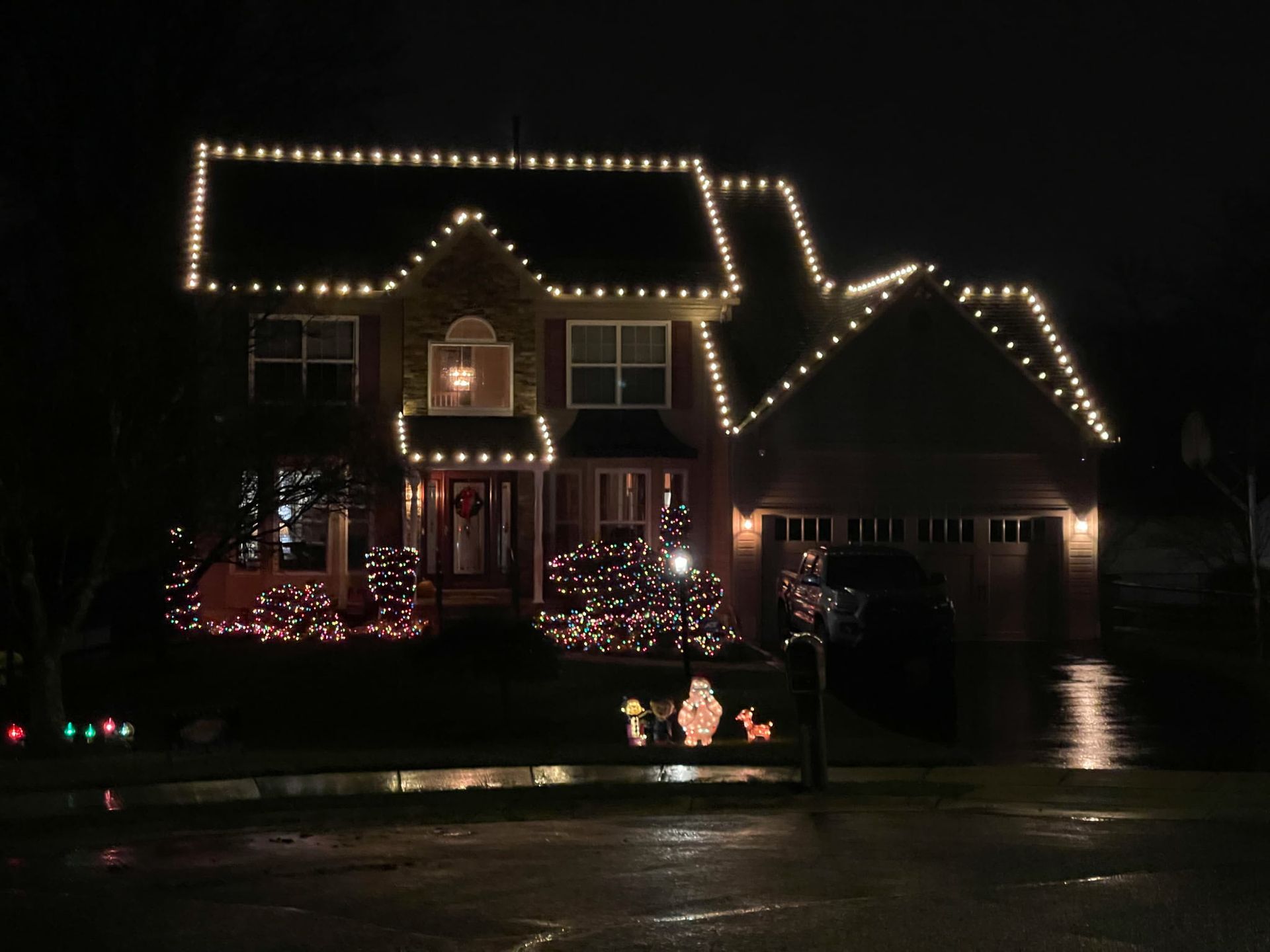 House decorated with Christmas lights and wreaths, illuminated at night.