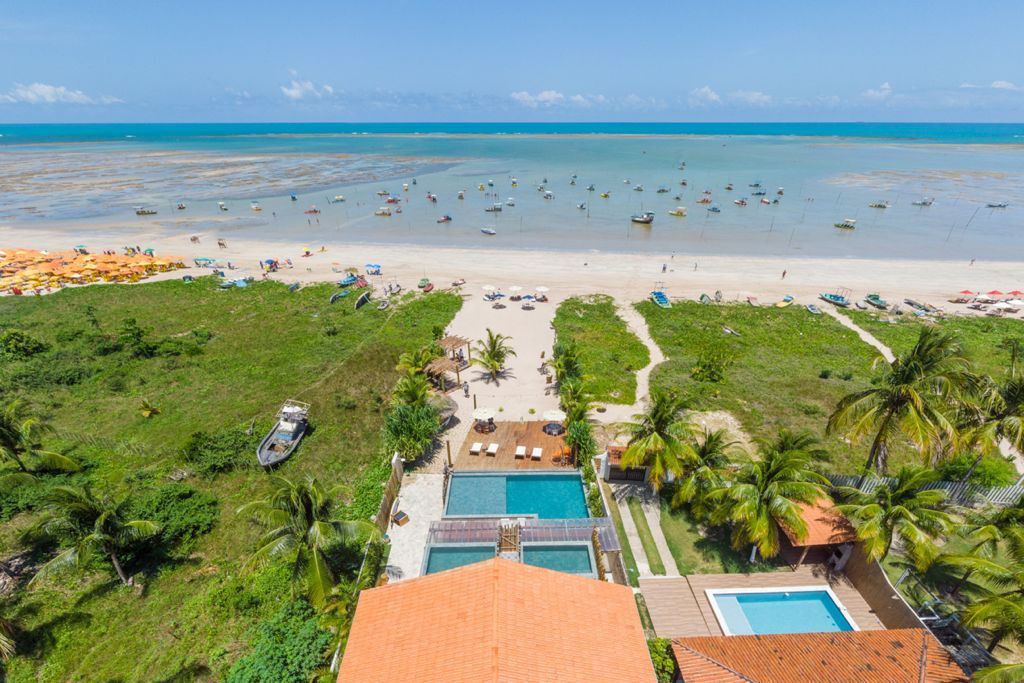 Resort de praia com piscinas, praia de areia e vista para o mar. Pessoas tomando sol e na água.Pousada Villa Italiana