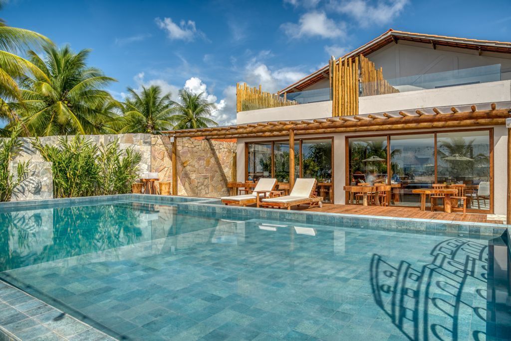 Vila com piscina, espreguiçadeiras e vegetação exuberante sob um céu azul.Pousada Villa Italiana