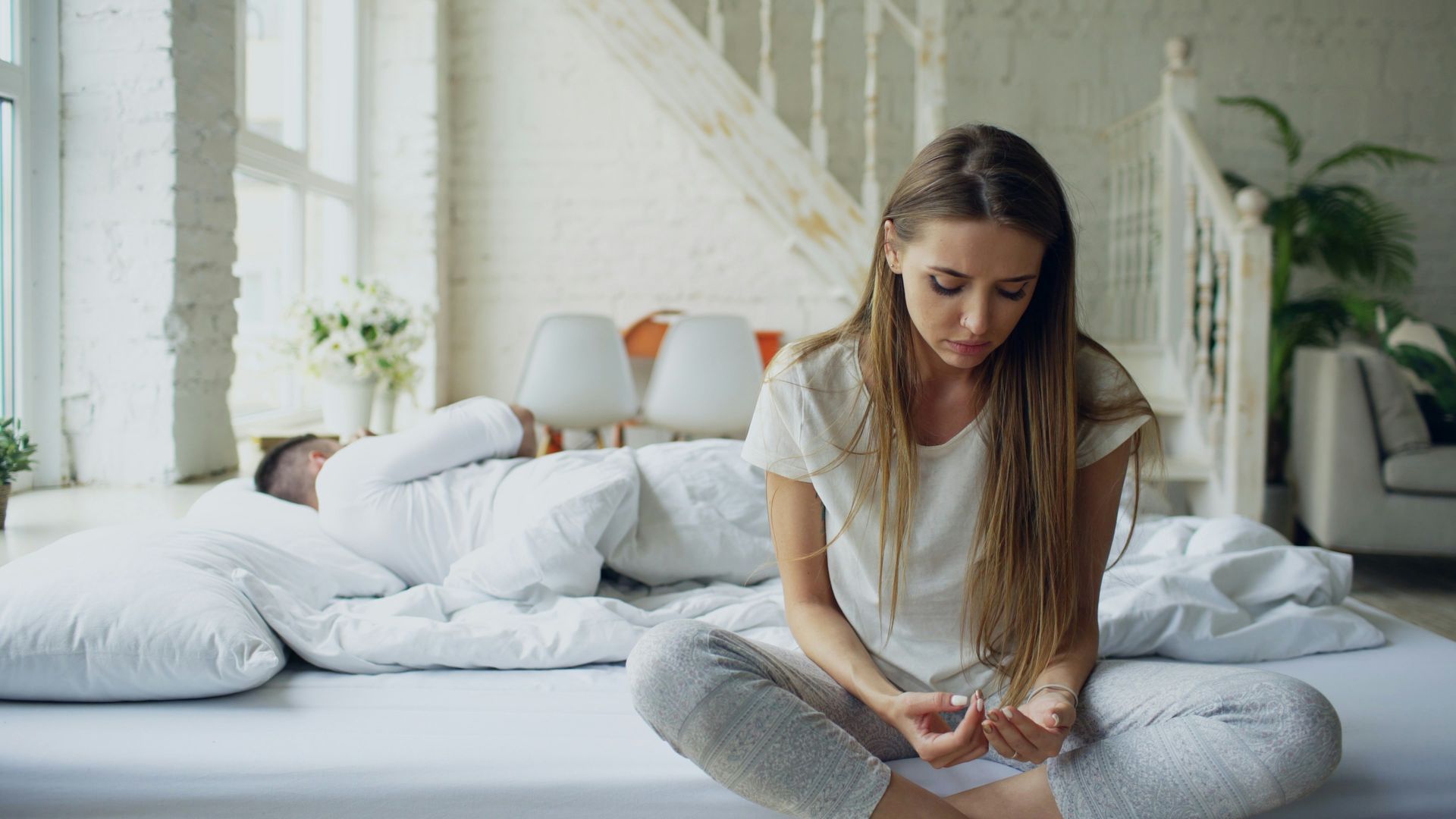 Woman sitting alone looking at hands on couch. 