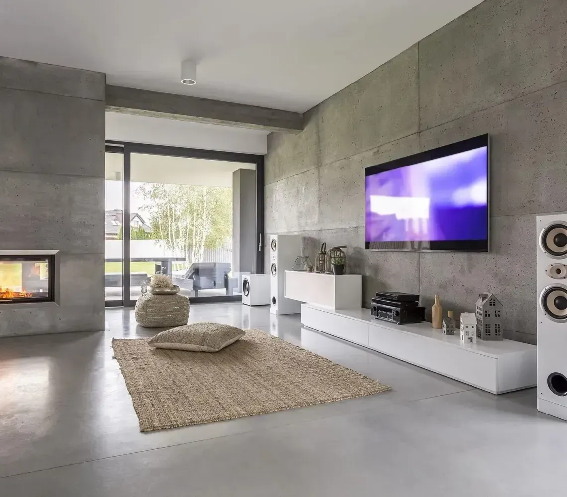 Modern living room with wall fireplace, large TV, white speakers, and gray minimalist decor