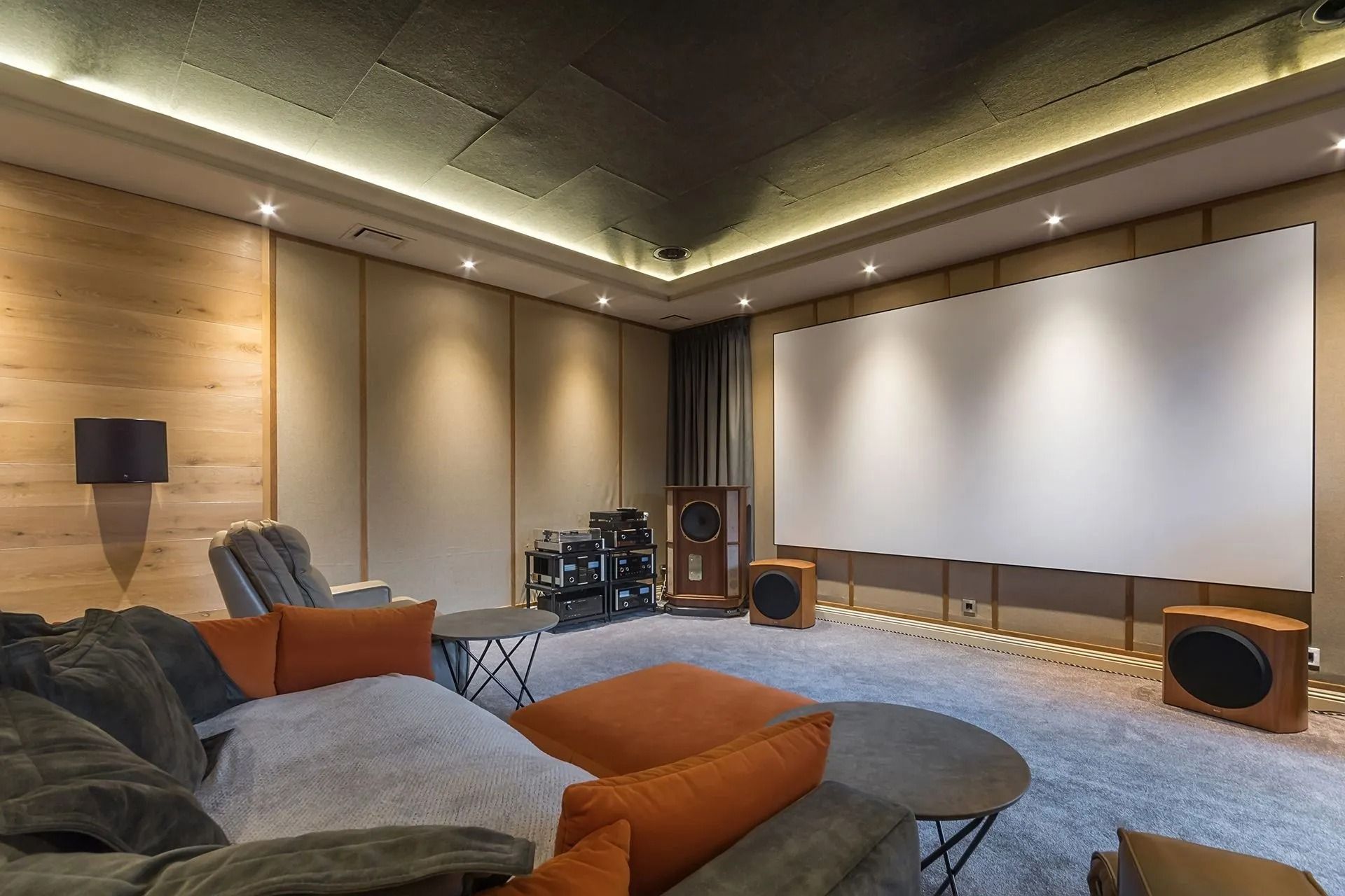 Modern home theater with large projection screen, cushioned seating, and wooden acoustic wall panels