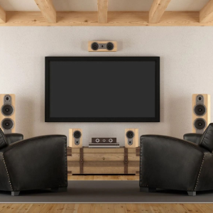 Modern home theater with large TV, surround speakers, and two black chairs facing the screen