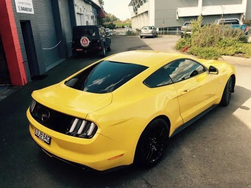 A Yellow Mustang is Parked in Front of a Building — Rod's Total Tint In Beresford, NSW