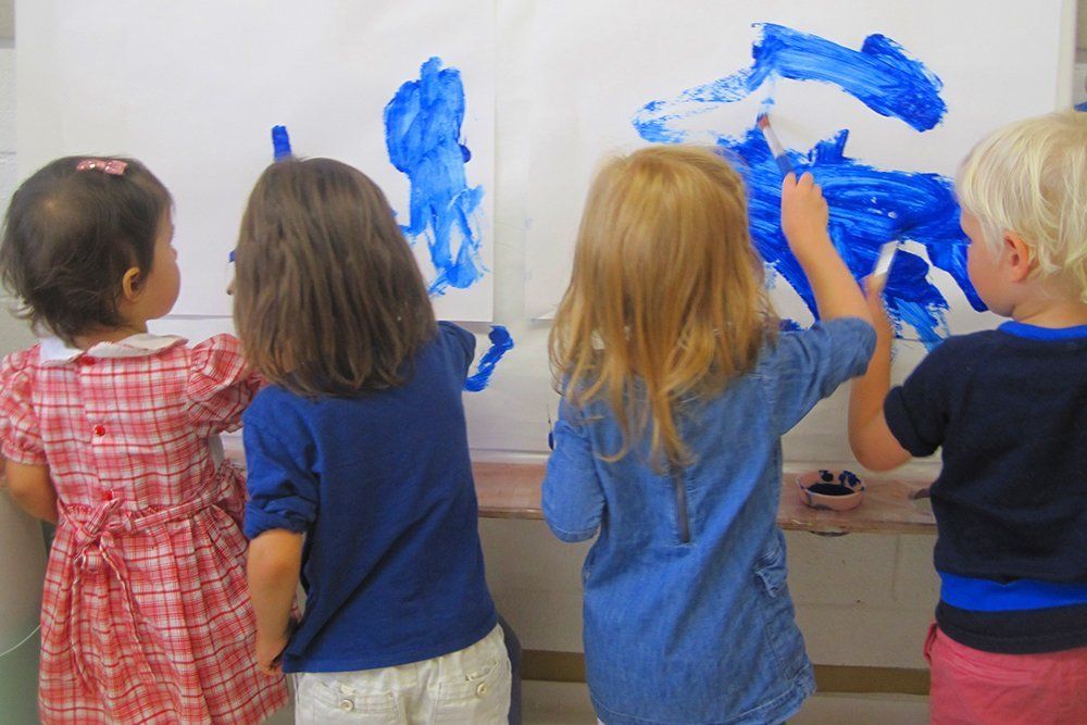 students painting on paper on the wall