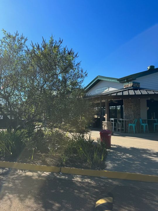 A building with a pergola and tables and chairs in front of it