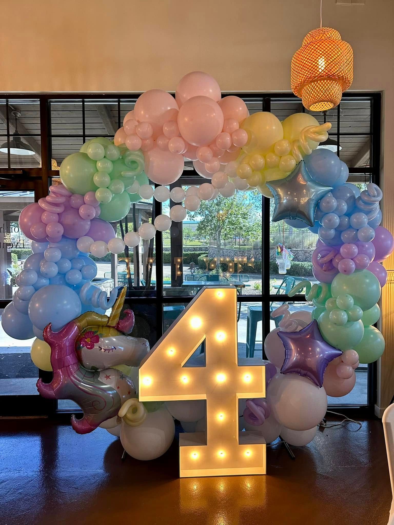 A room filled with balloons and a lighted number four.