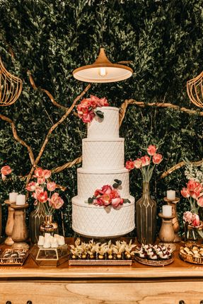A wedding cake is sitting on top of a wooden table.
