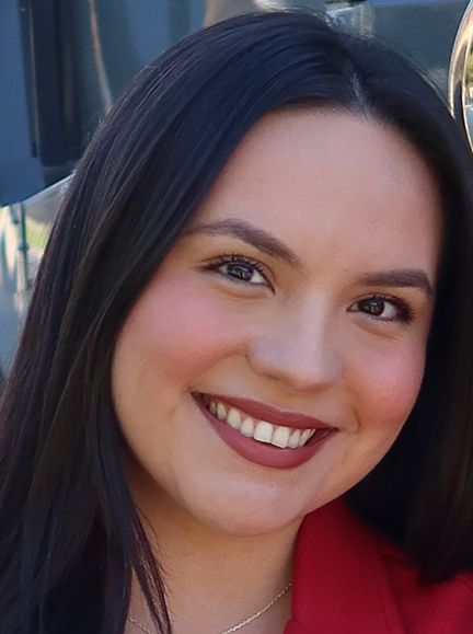 A woman wearing an orange and yellow safety vest smiles for the camera