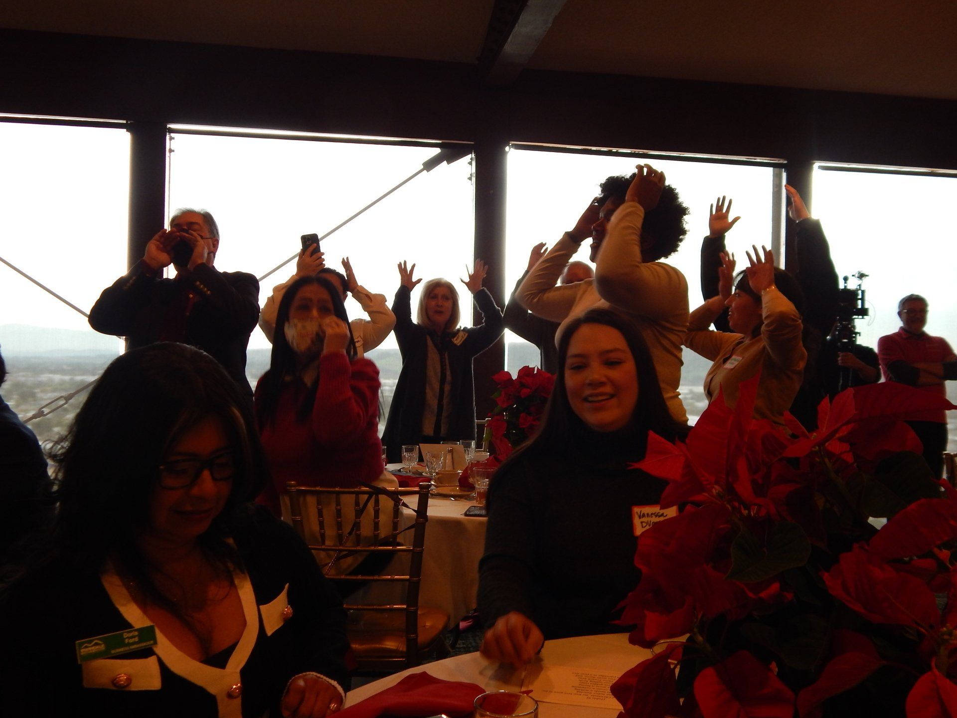 A group of people are sitting at a table with their hands in the air