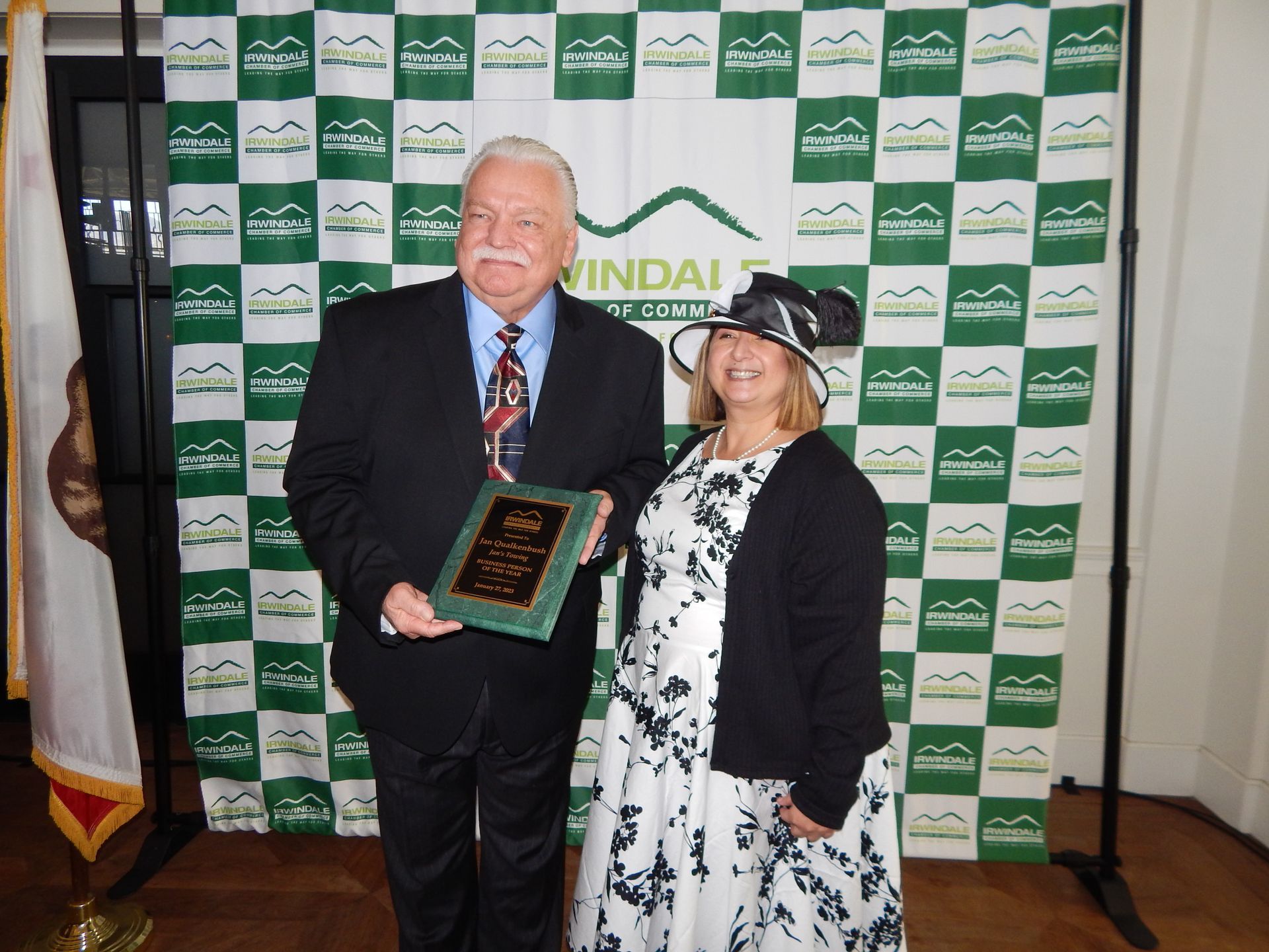 A man and woman standing in front of a green and white checkered backdrop