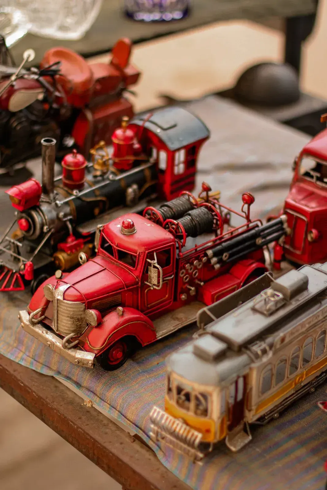 Miniature red fire trucks and train cars displayed on a table at a model exhibit