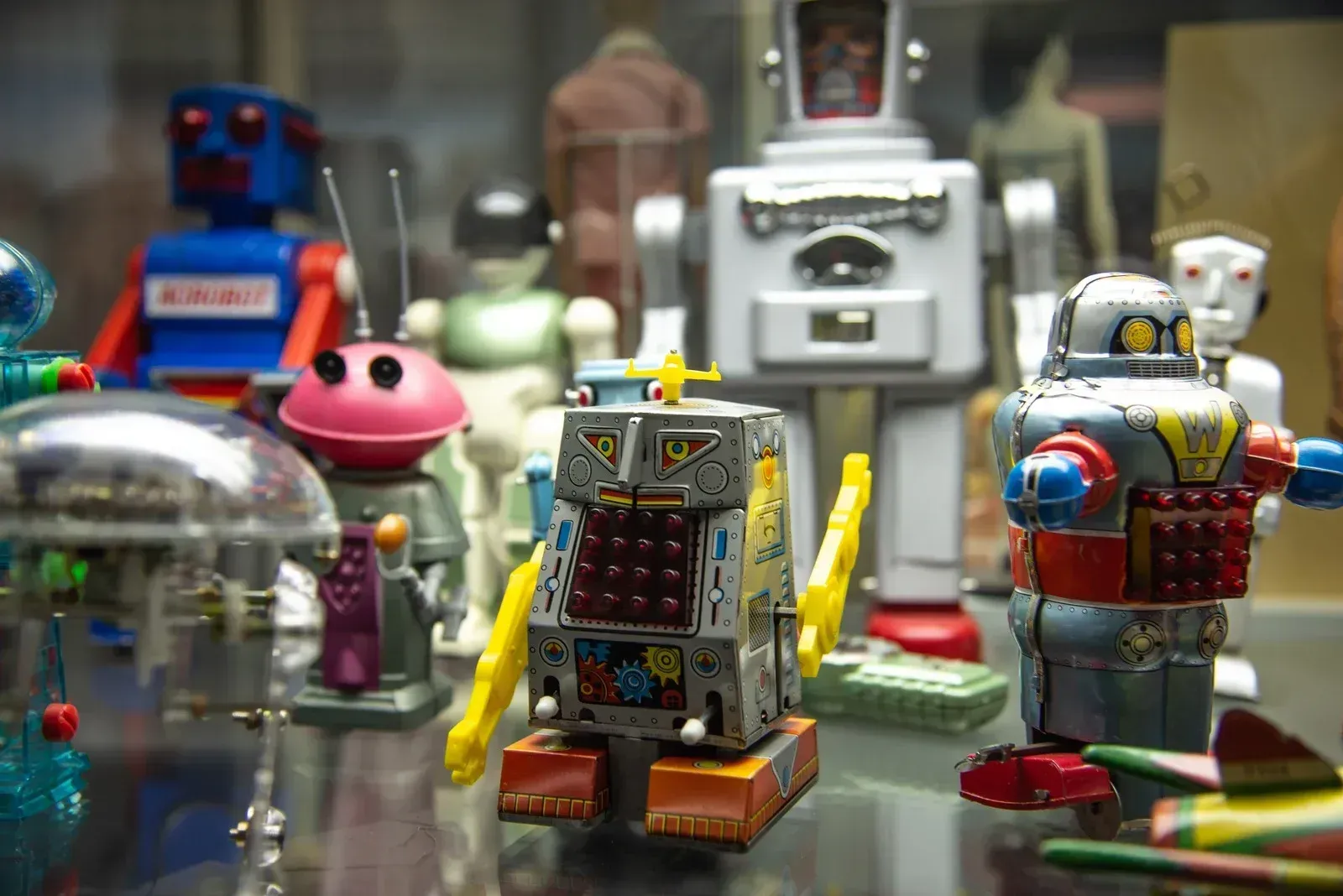 Miniature toy robots in colorful display cases, with a silver robot and a blue red robot in front