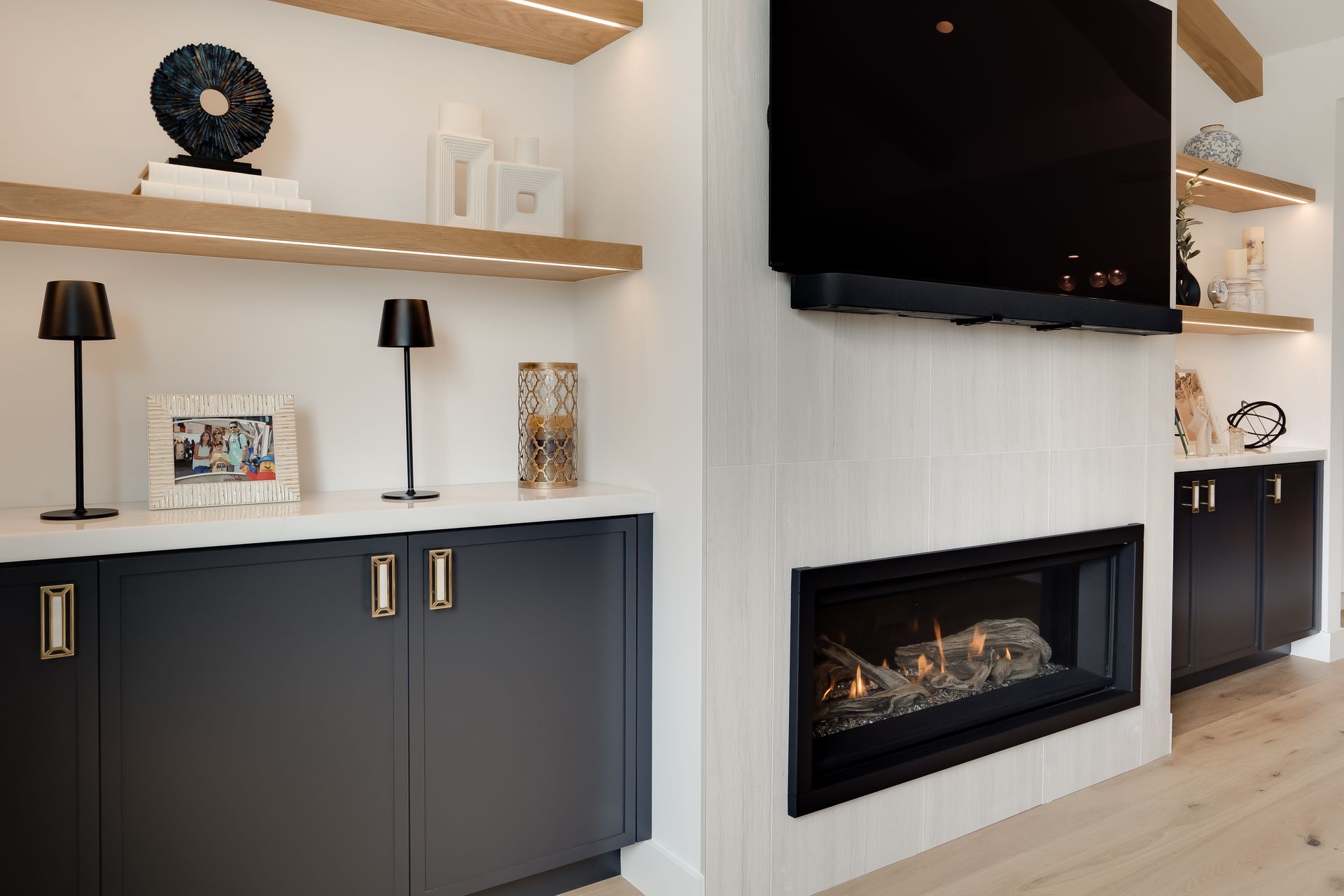 Modern living room with a fireplace, TV, and floating shelves with decorative items.