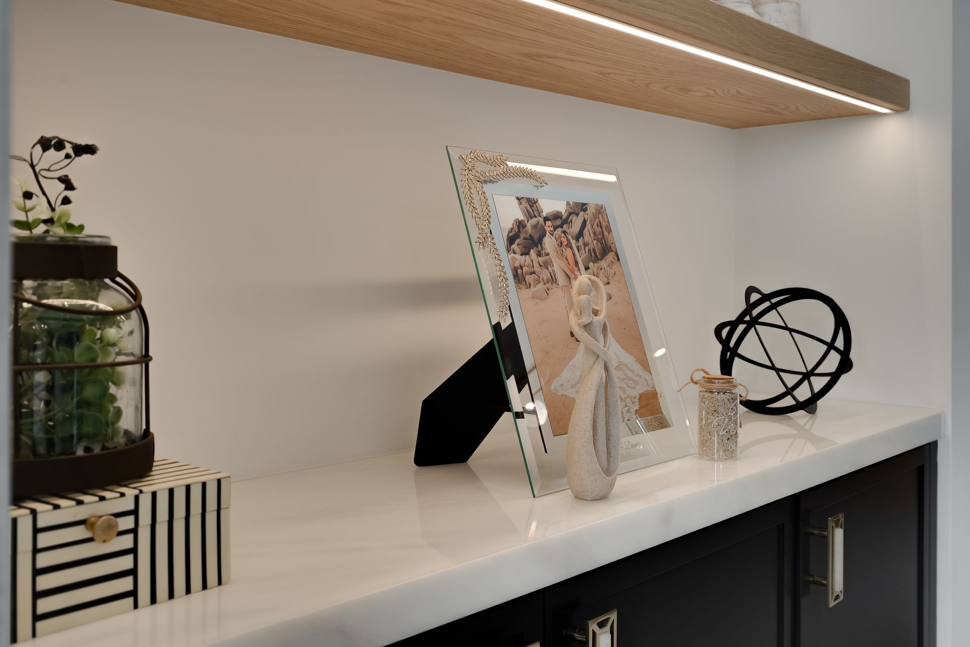 A shelf with a framed photo, decor, and a light fixture.